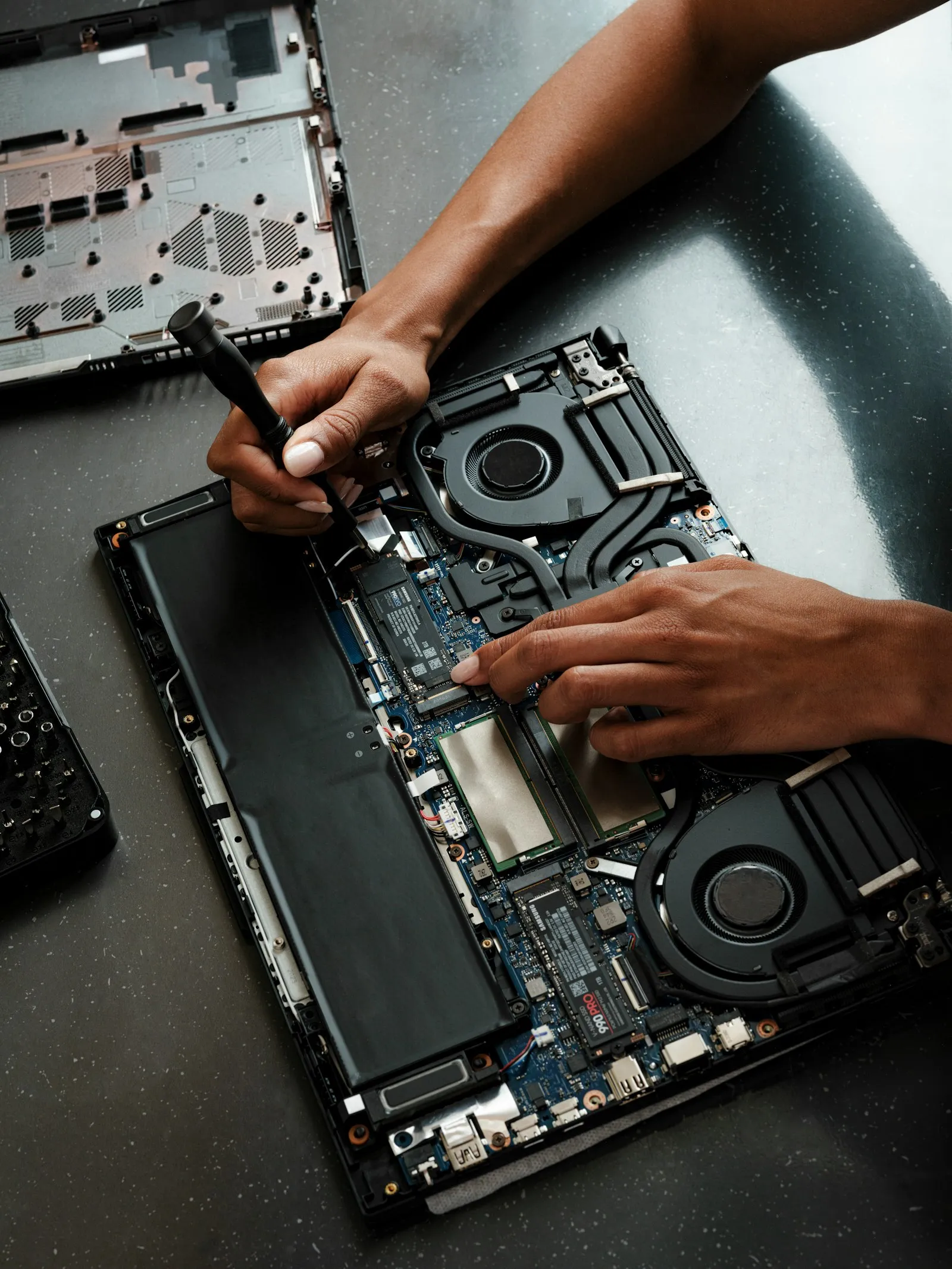 Teknisi membongkar dan memeriksa bagian dalam laptop di meja kerja